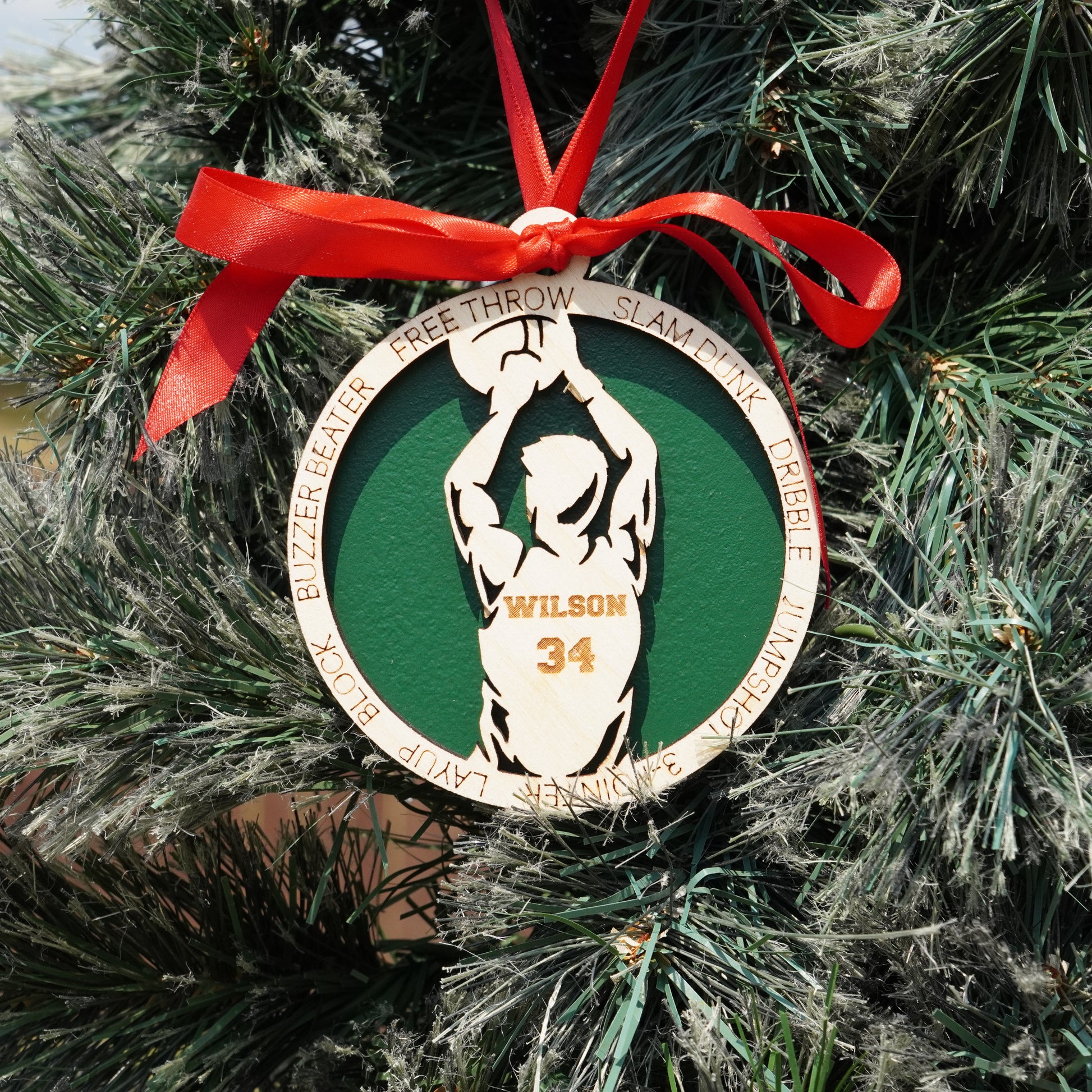 Basketball ornament with a player design and red ribbon on a Christmas tree.