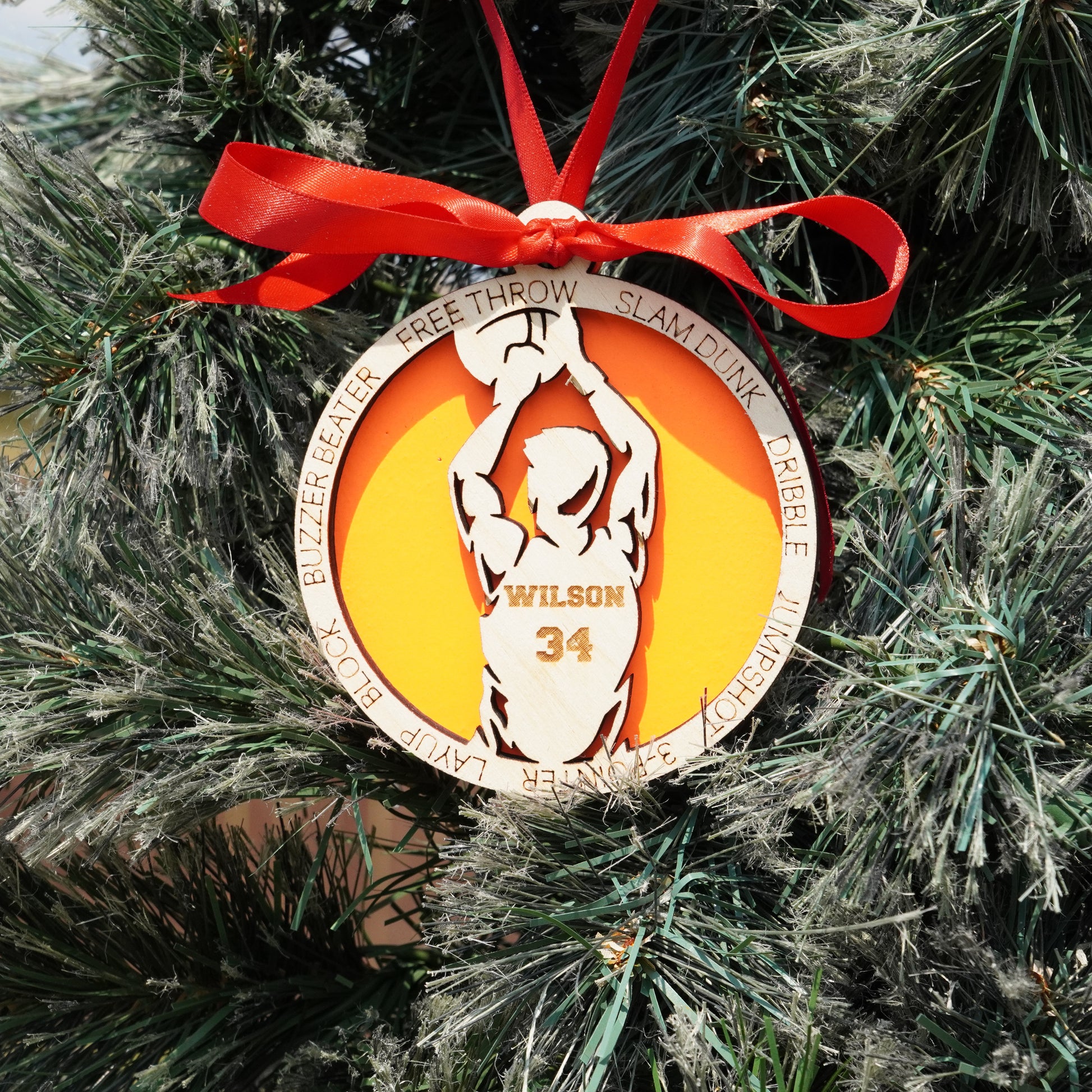 Decorative basketball ornament with a red ribbon on a Christmas tree.