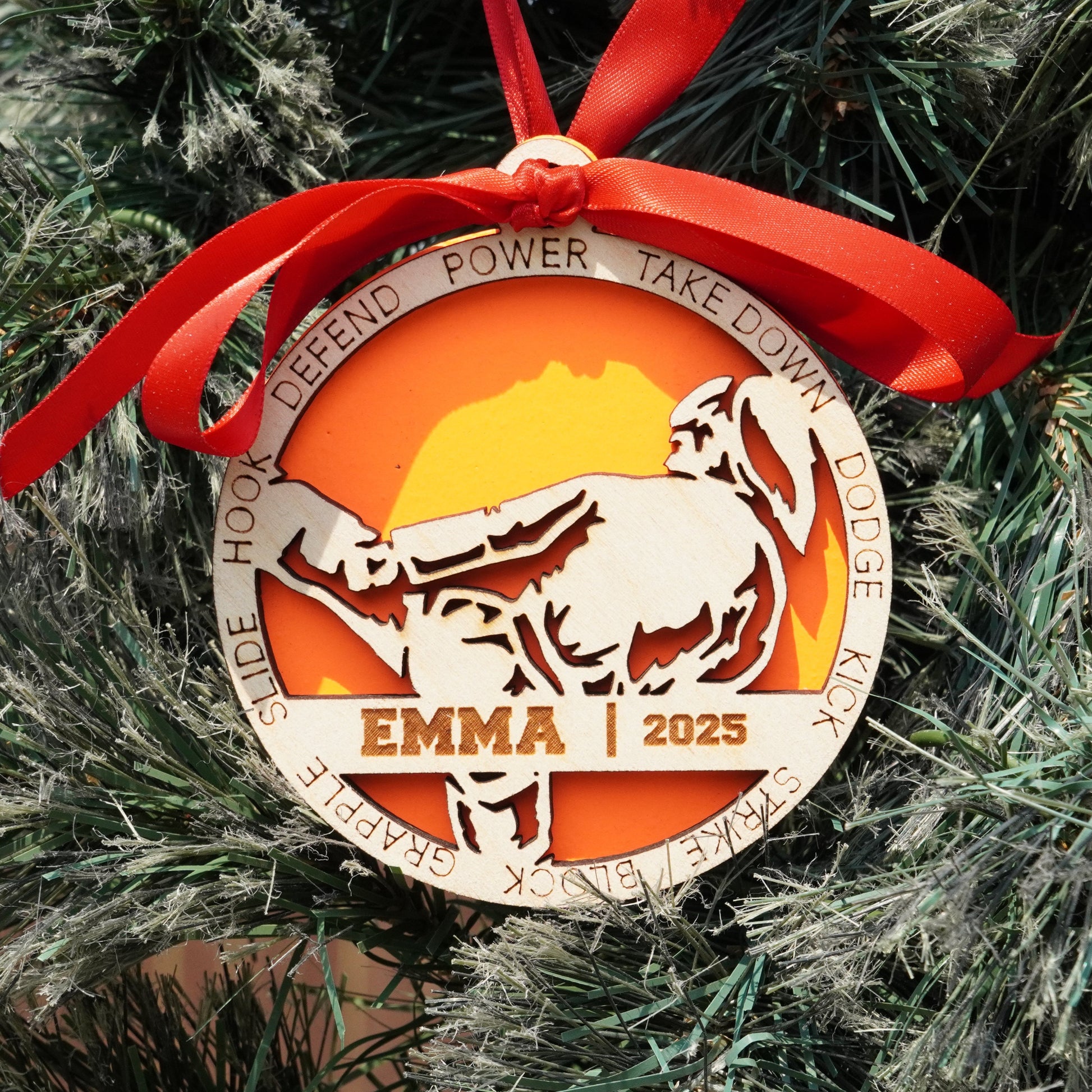 Decorative Christmas ornament with a bull design and 'EMMA 2025' text, hanging on a tree.
