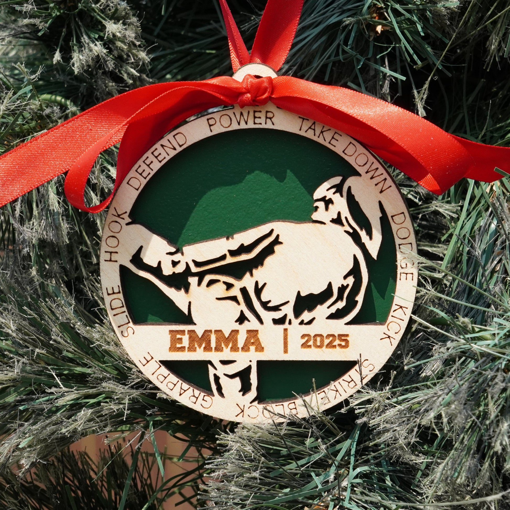 Decorative Christmas ornament with a dog silhouette and text on a green background, hanging on a tree.