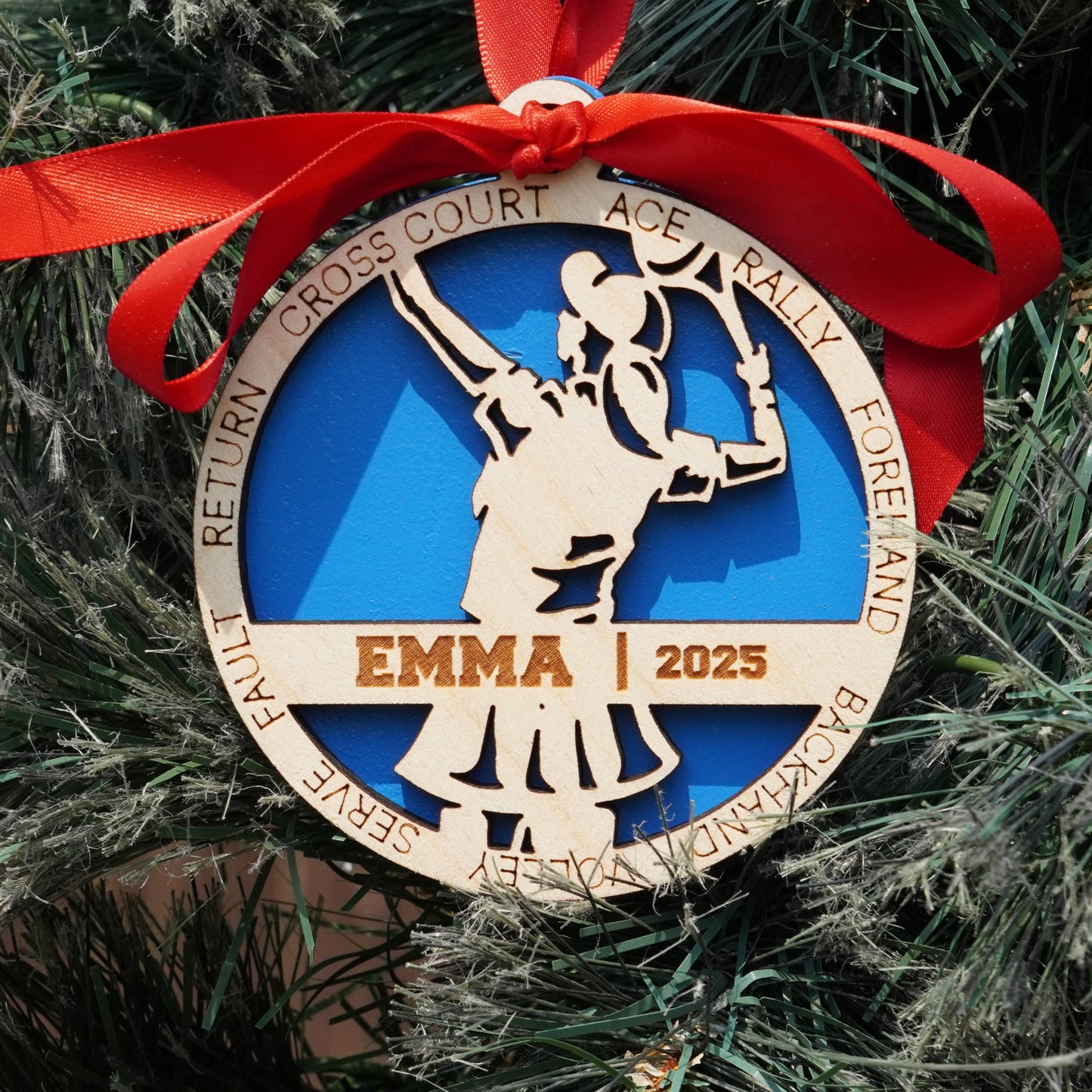 Decorative ornament with a red ribbon on a Christmas tree, featuring the name 'EMMA' and the year '2023'.