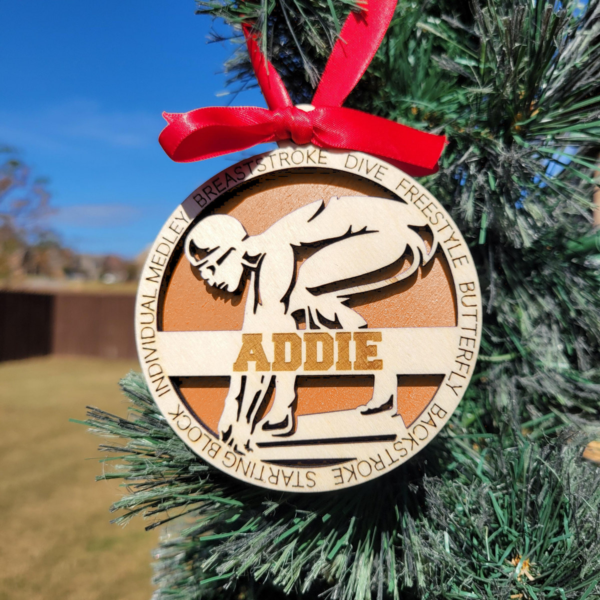 Personalized swimmer ornament with orange backing on a Christmas tree