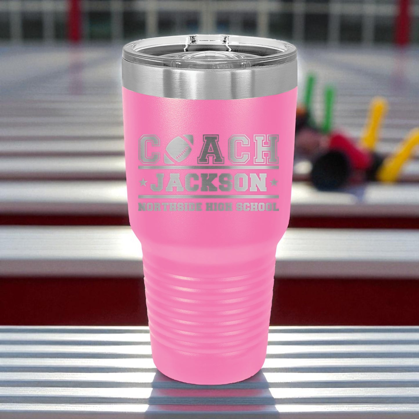 Pink tumbler with 'Coach Jackson' engraving on a metallic surface