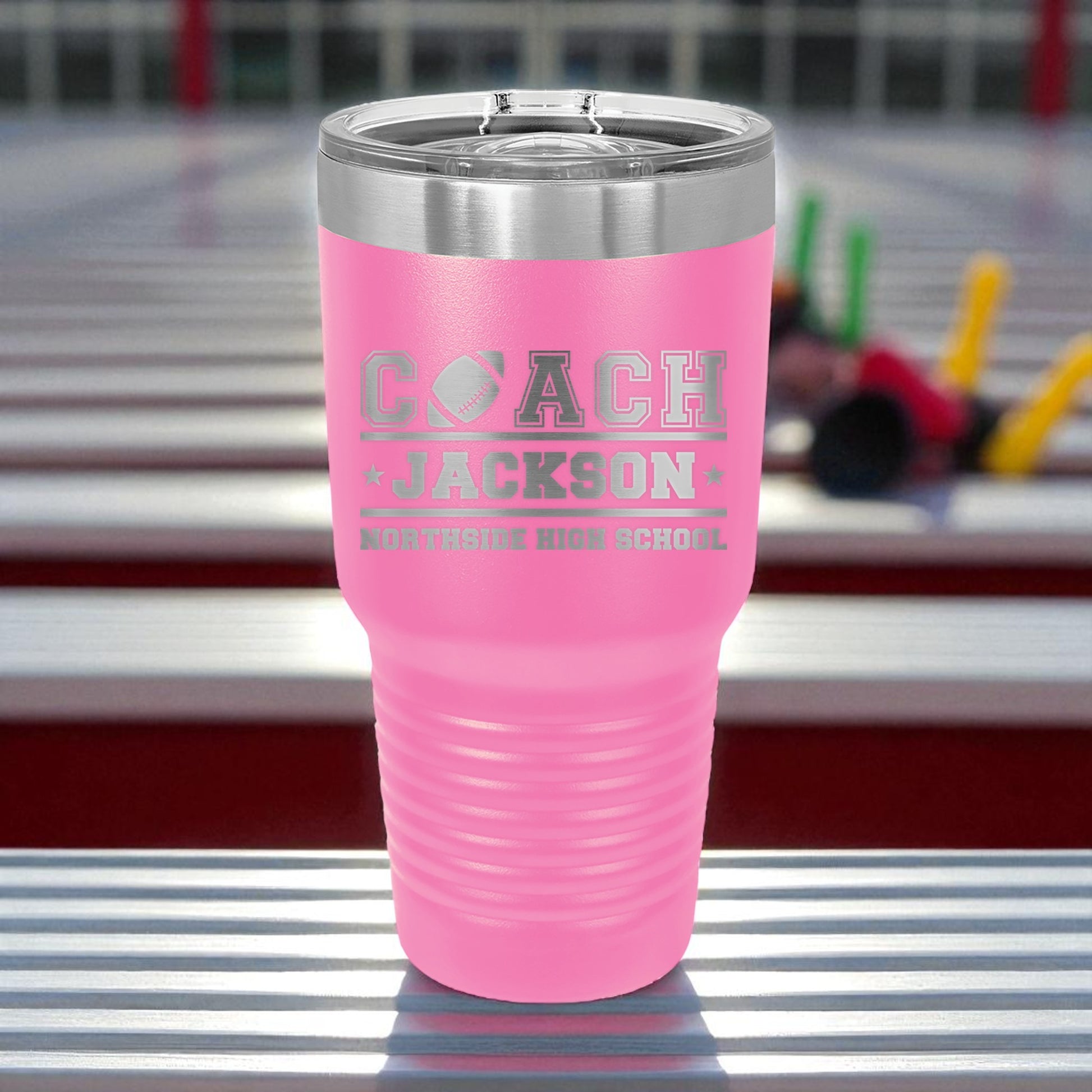 Pink tumbler with 'Coach Jackson' engraving on a metallic surface
