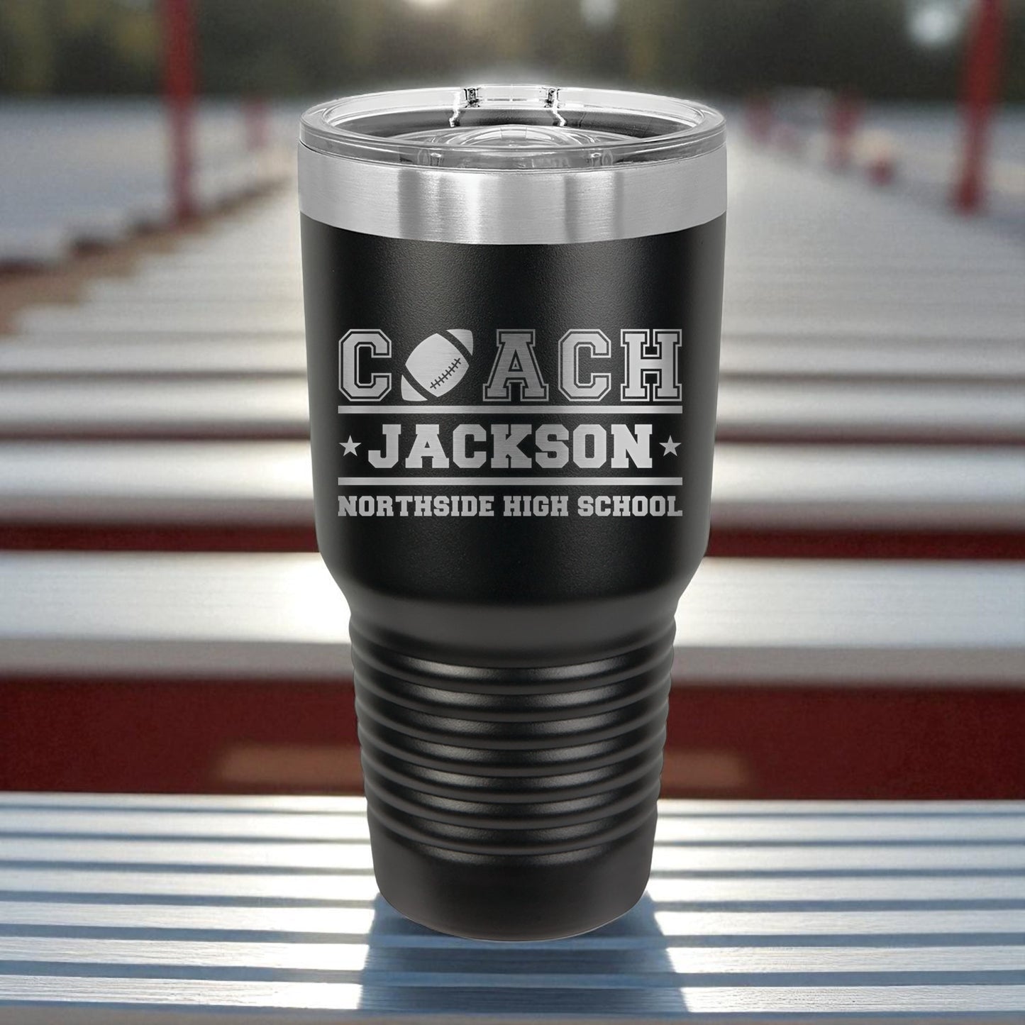 Black tumbler with 'Coach Jackson Northside High School' engraving on a metallic surface.
