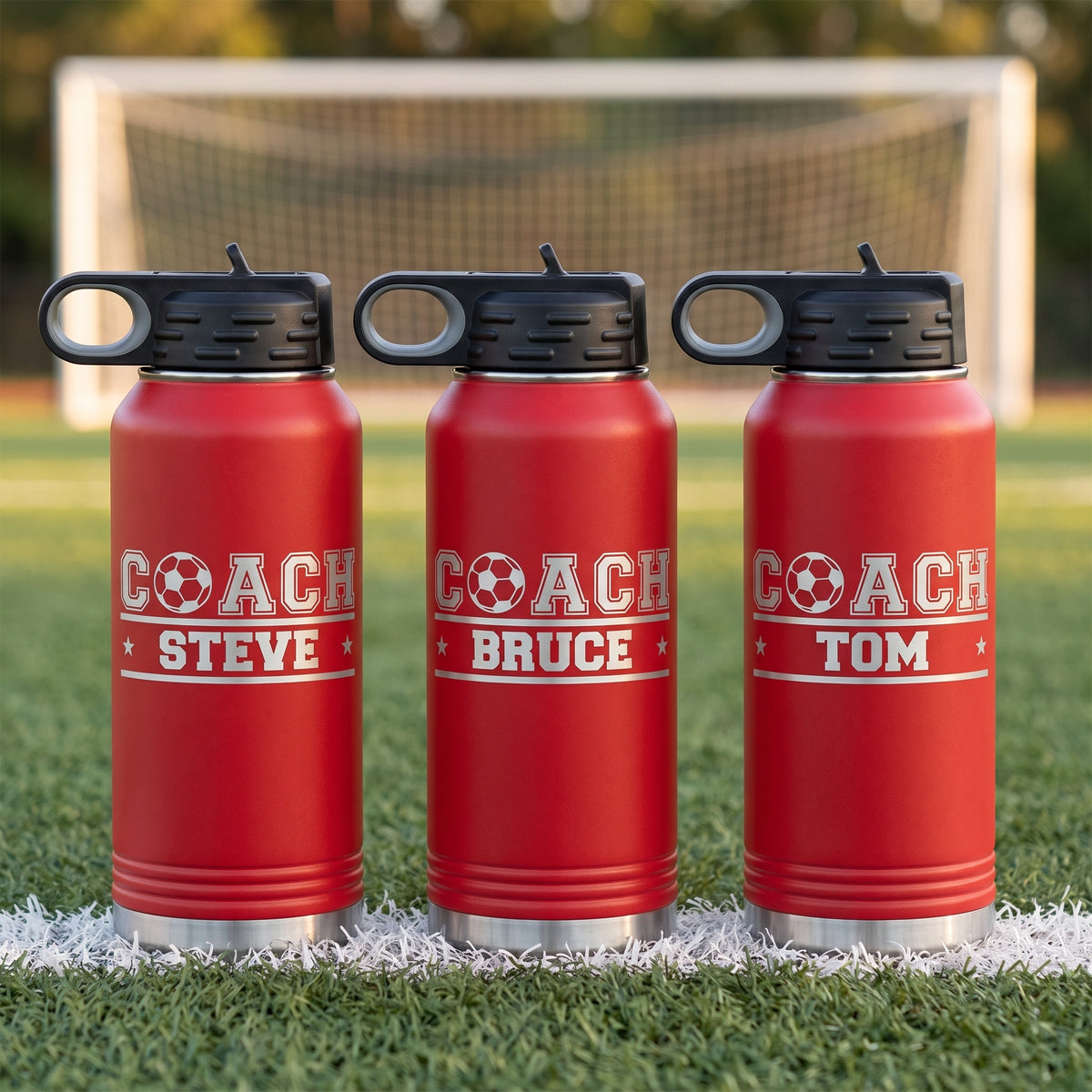 Red personalized soccer coach water bottles engraved with the soccer ball COACH logo and each coach name