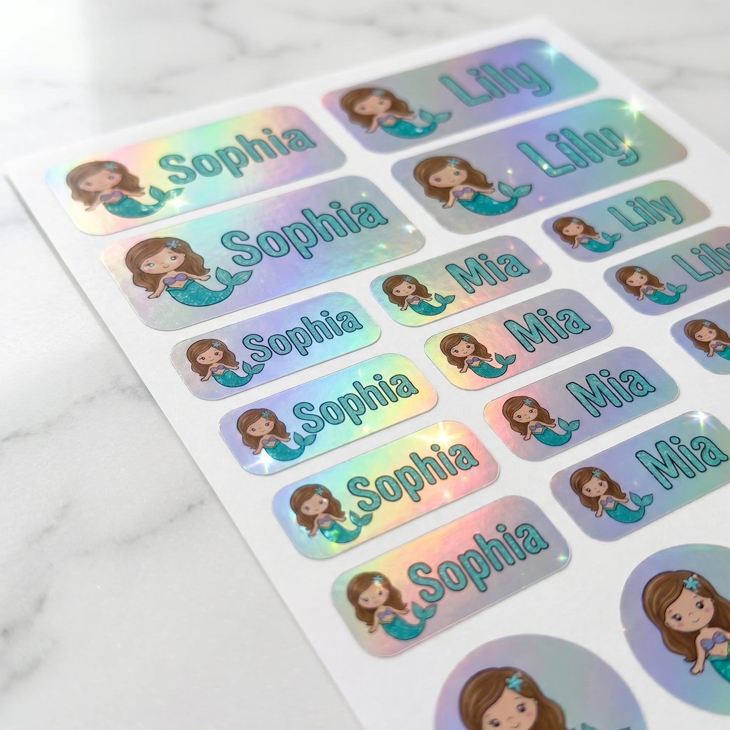 Holographic mermaid name label sticker sheet close-up with rainbow shimmer