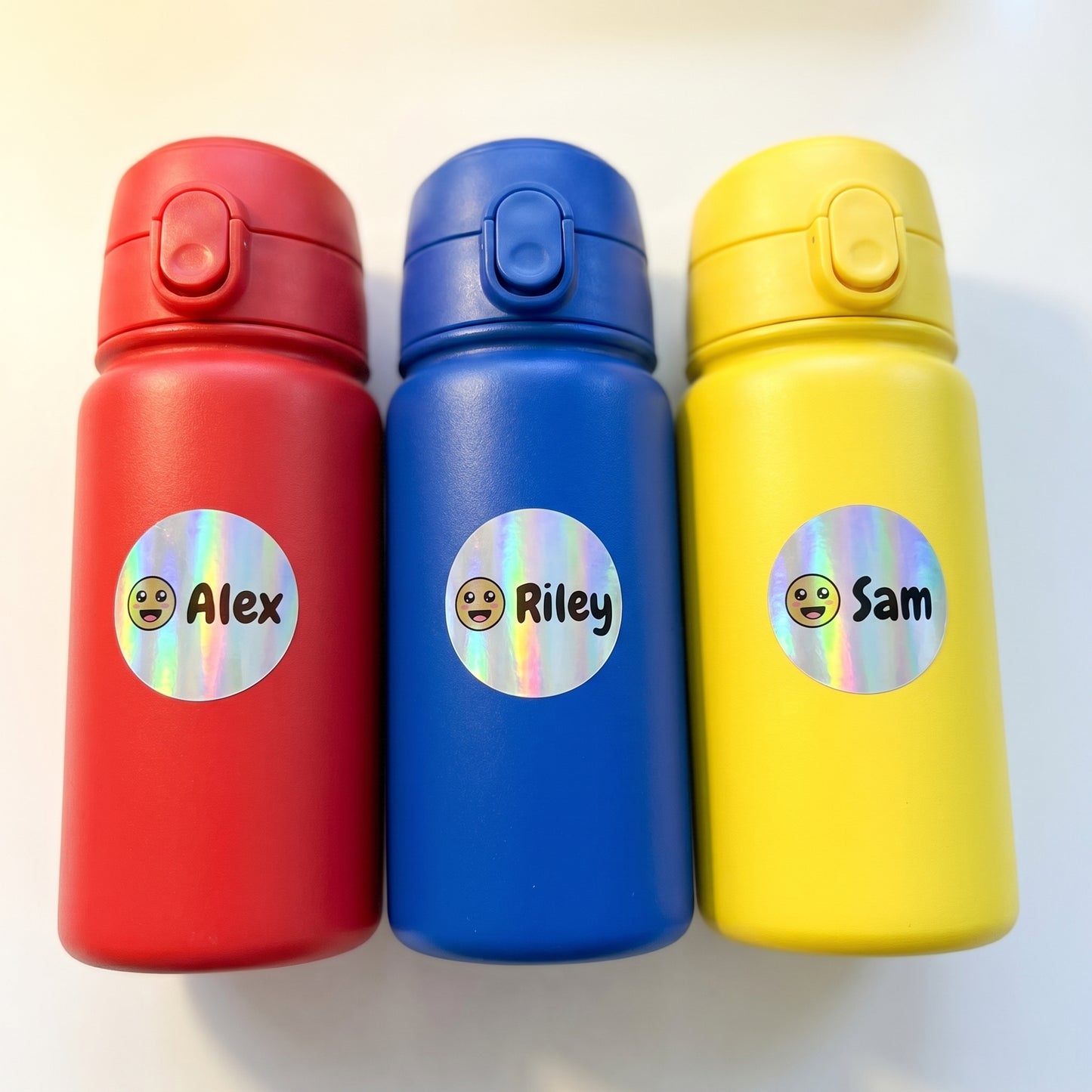 Personalized smiley name labels on three kids water bottles