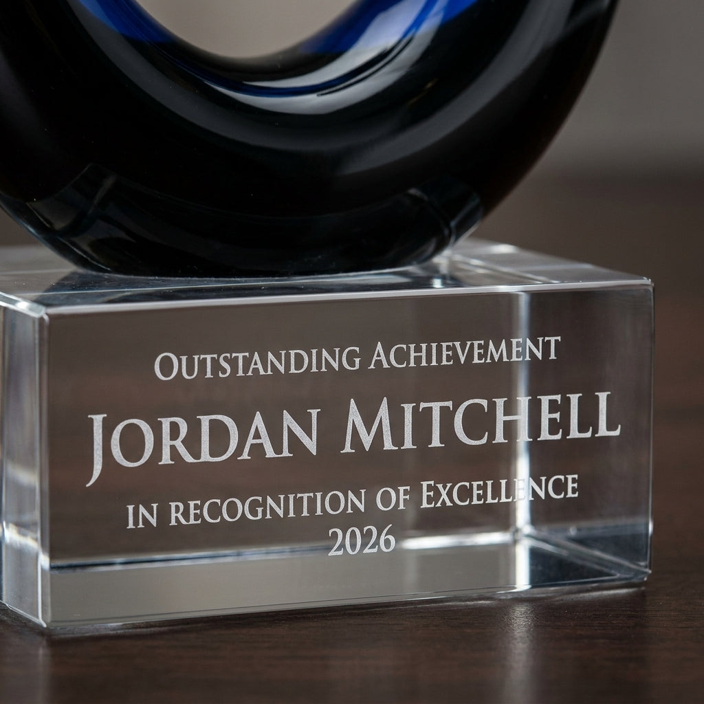 Close-up of the custom laser engraving on a personalized Midnight Blue Flame Knot art glass award, showing crisp permanent personalization