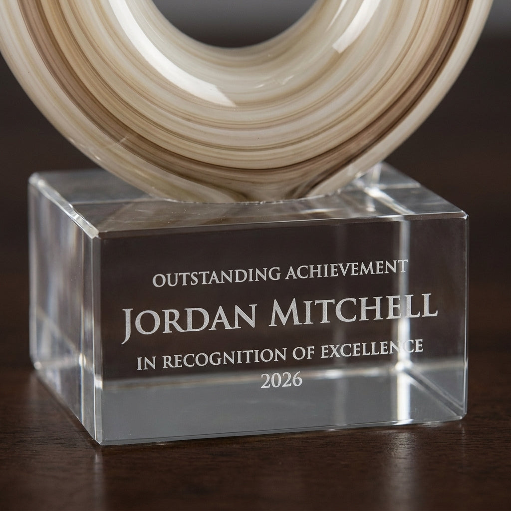Close-up of the custom laser engraving on a personalized Amber Caramel Infinity art glass award, showing crisp permanent personalization