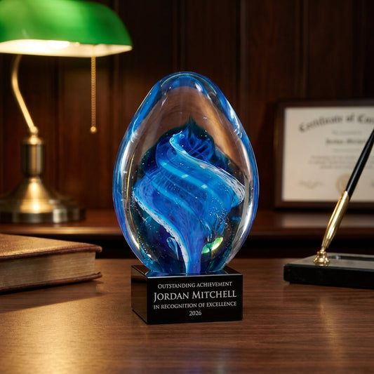 Personalized Sculpture art glass award on a warm executive desk with a green banker's lamp, engraved corporate recognition and retirement gift