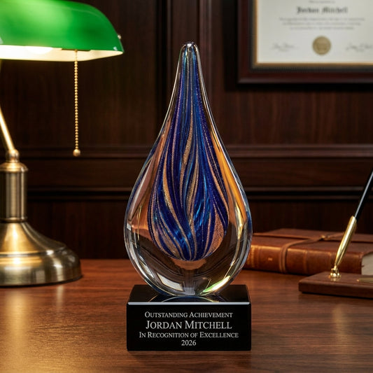 Personalized Sapphire Gold Raindrop art glass award on a warm executive desk with a green banker's lamp, engraved corporate recognition and retirement gift