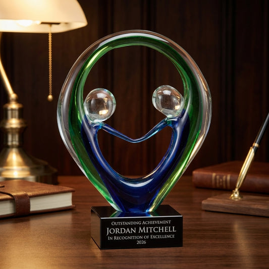 Personalized Sculpture art glass award on a warm executive desk with a green banker's lamp, engraved corporate recognition and retirement gift