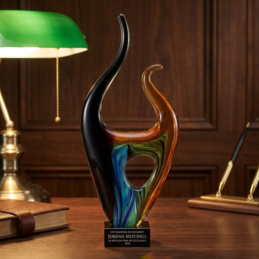 Personalized Sculpture art glass award on a warm executive desk with a green banker's lamp, engraved corporate recognition and retirement gift