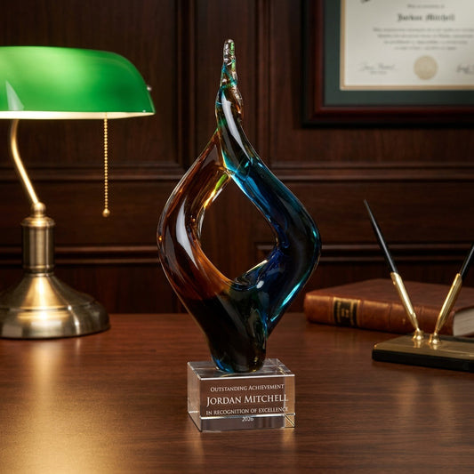 Personalized Amber Blue Double Flame art glass award on a warm executive desk with a green banker's lamp, engraved corporate recognition and retirement gift