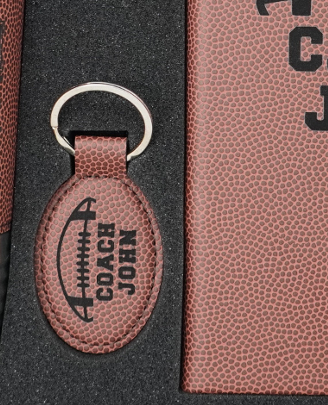 Football coach keychain engraved COACH JOHN shown in the foam insert of the Football Coach Gift Box