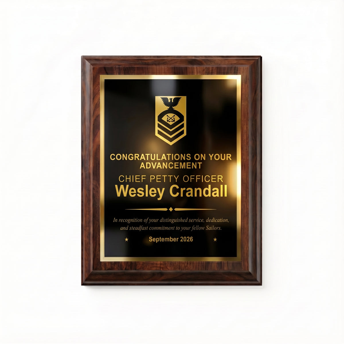Navy Chief Petty Officer advancement plaque, straight-on view of the gold engraved rank insignia, name, diamond divider, message, and date on the black plate