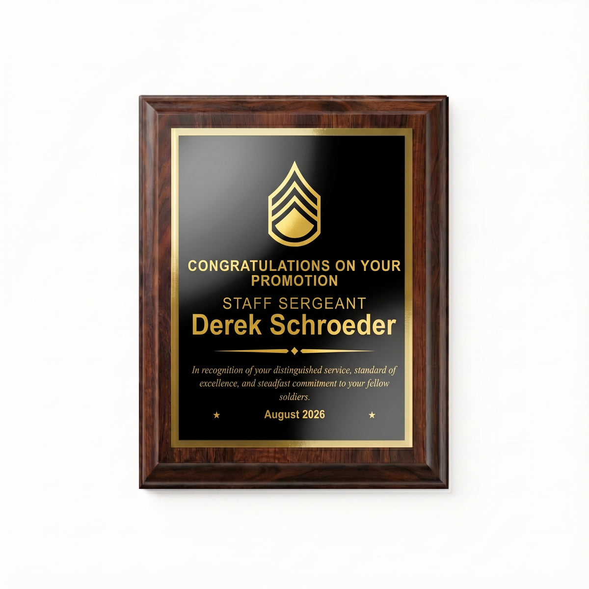 Army Staff Sergeant promotion plaque, straight-on view of the gold engraved rank insignia, name, diamond divider, message, and date on the black plate