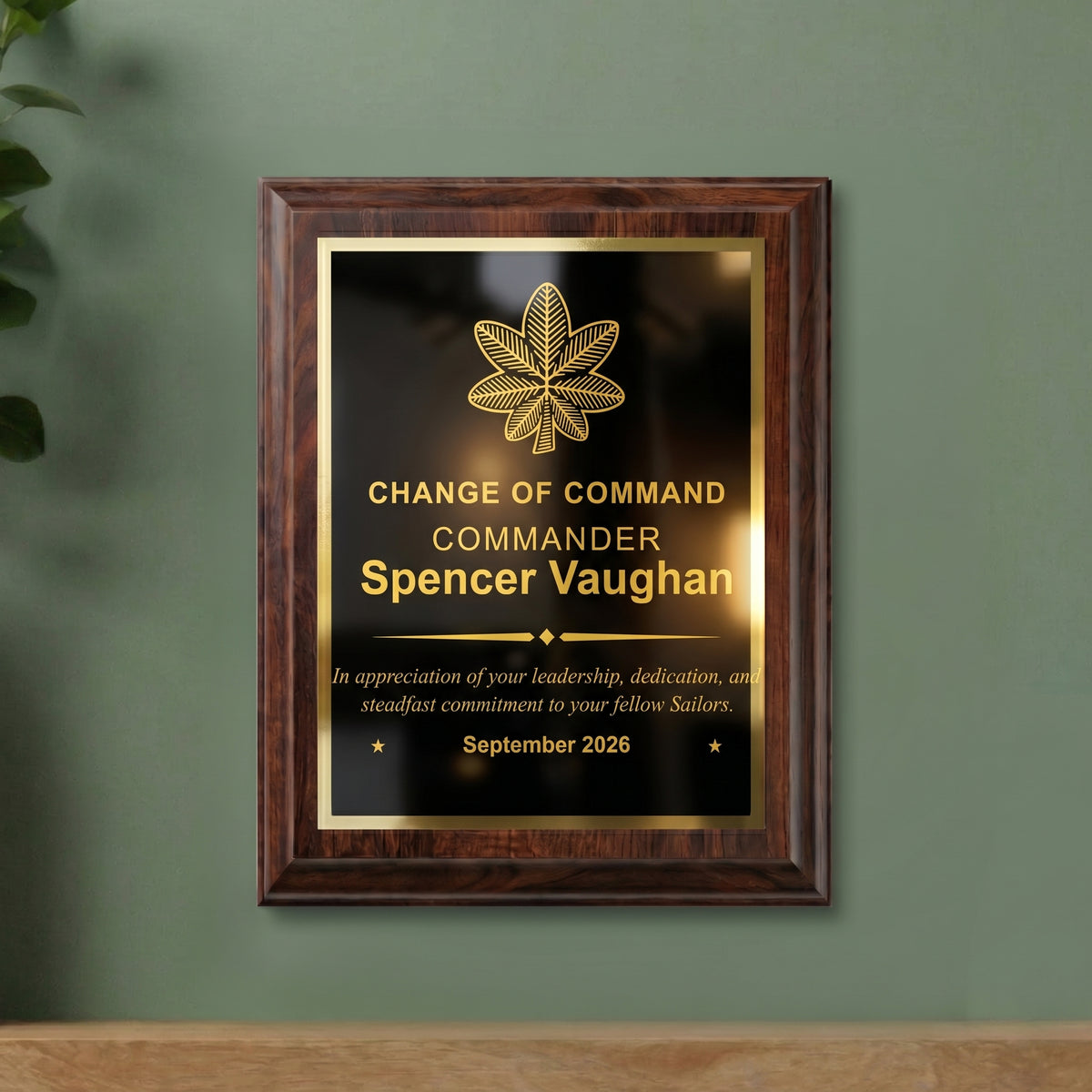 Navy Commander change of command plaque hanging on a wall, cherry finish with the officer insignia, name, and date engraved in gold