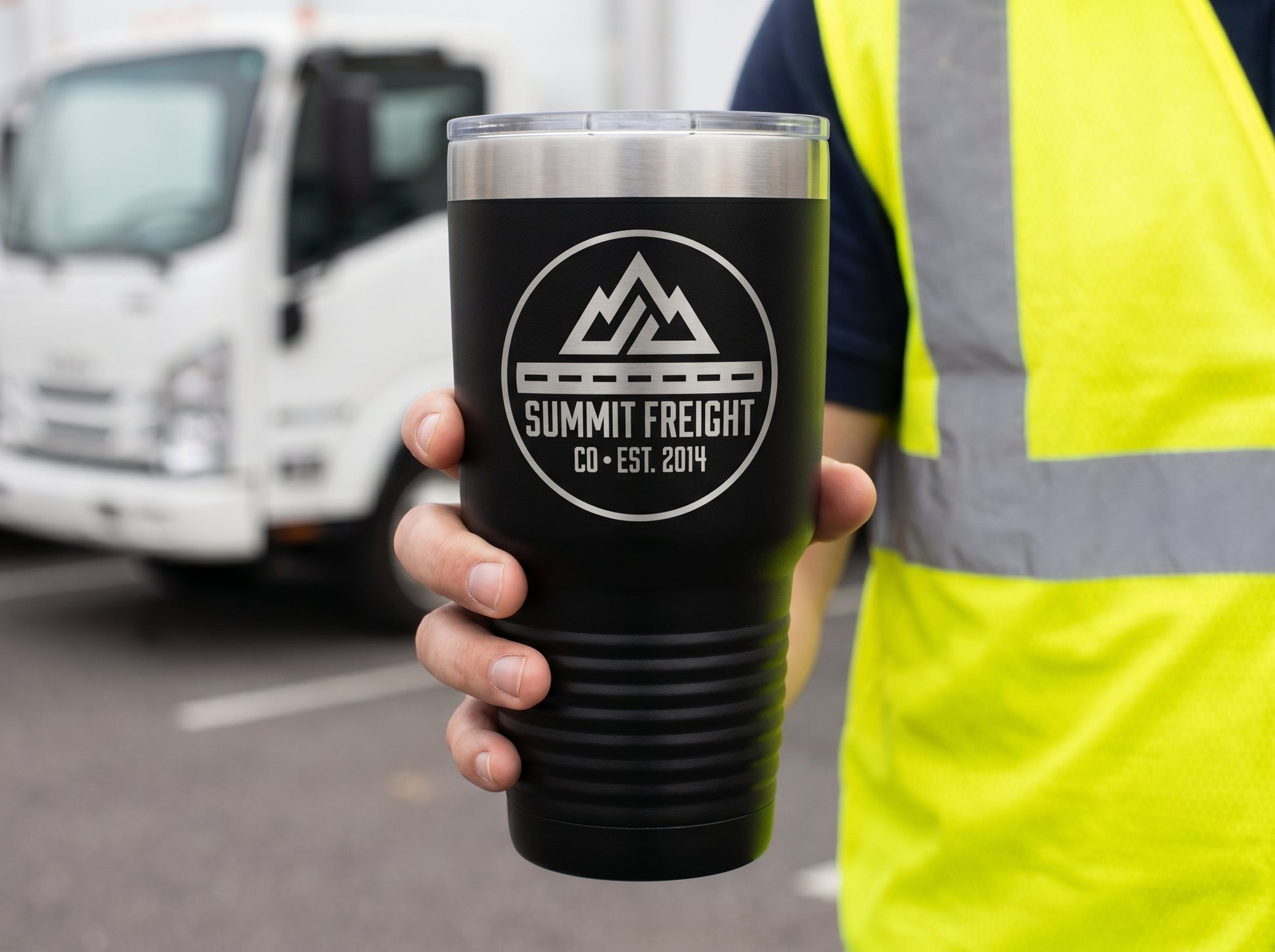 Fleet driver holding a branded 30oz tumbler by a delivery truck