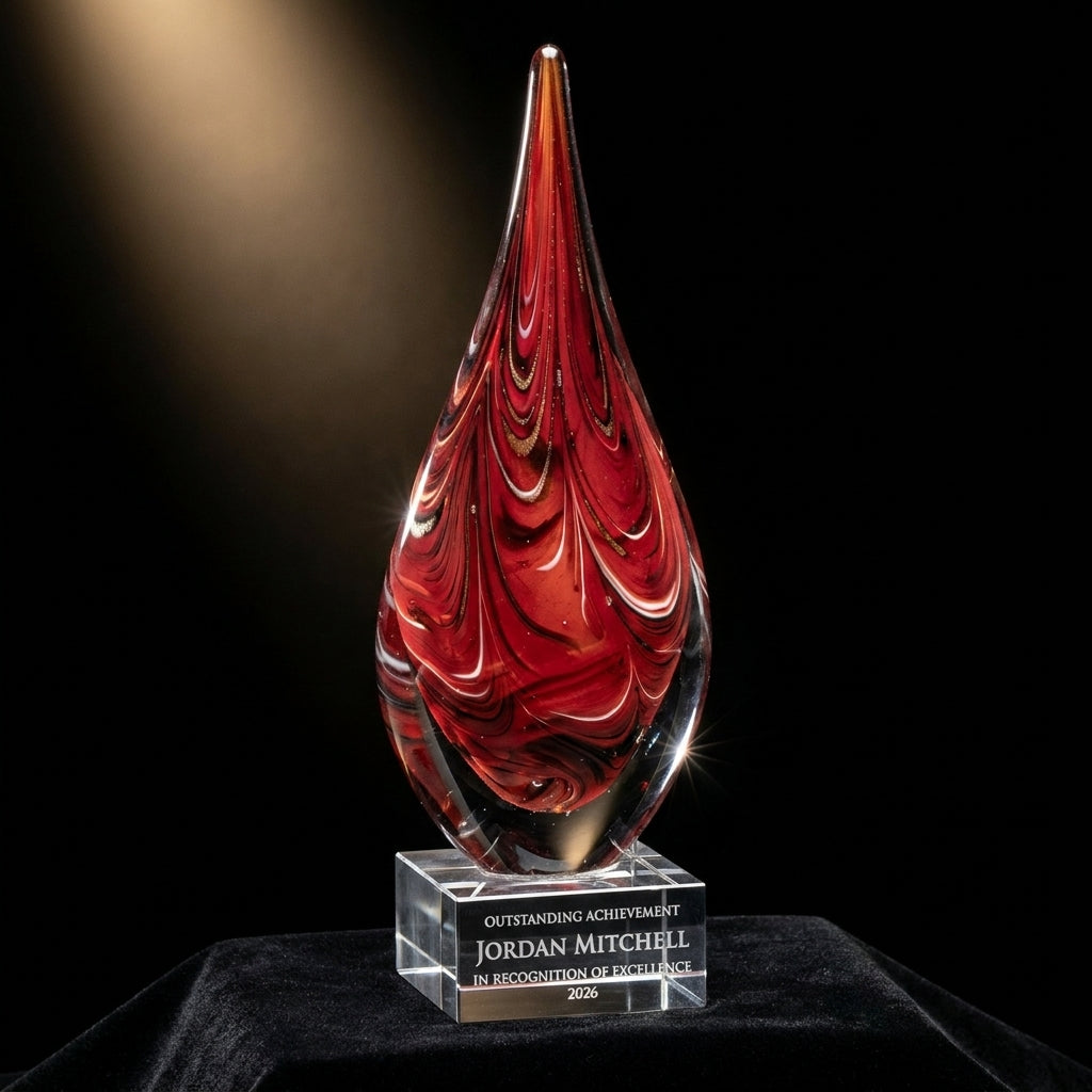 Personalized Red Swirl Teardrop art glass award on black velvet under awards-ceremony spotlight, engraved champion and lifetime achievement award