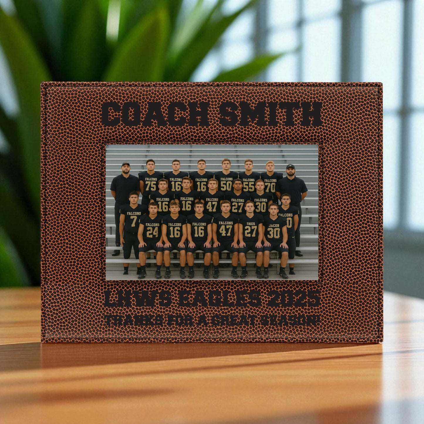 Football-themed photo frame with a team picture and engraved text on a wooden surface.