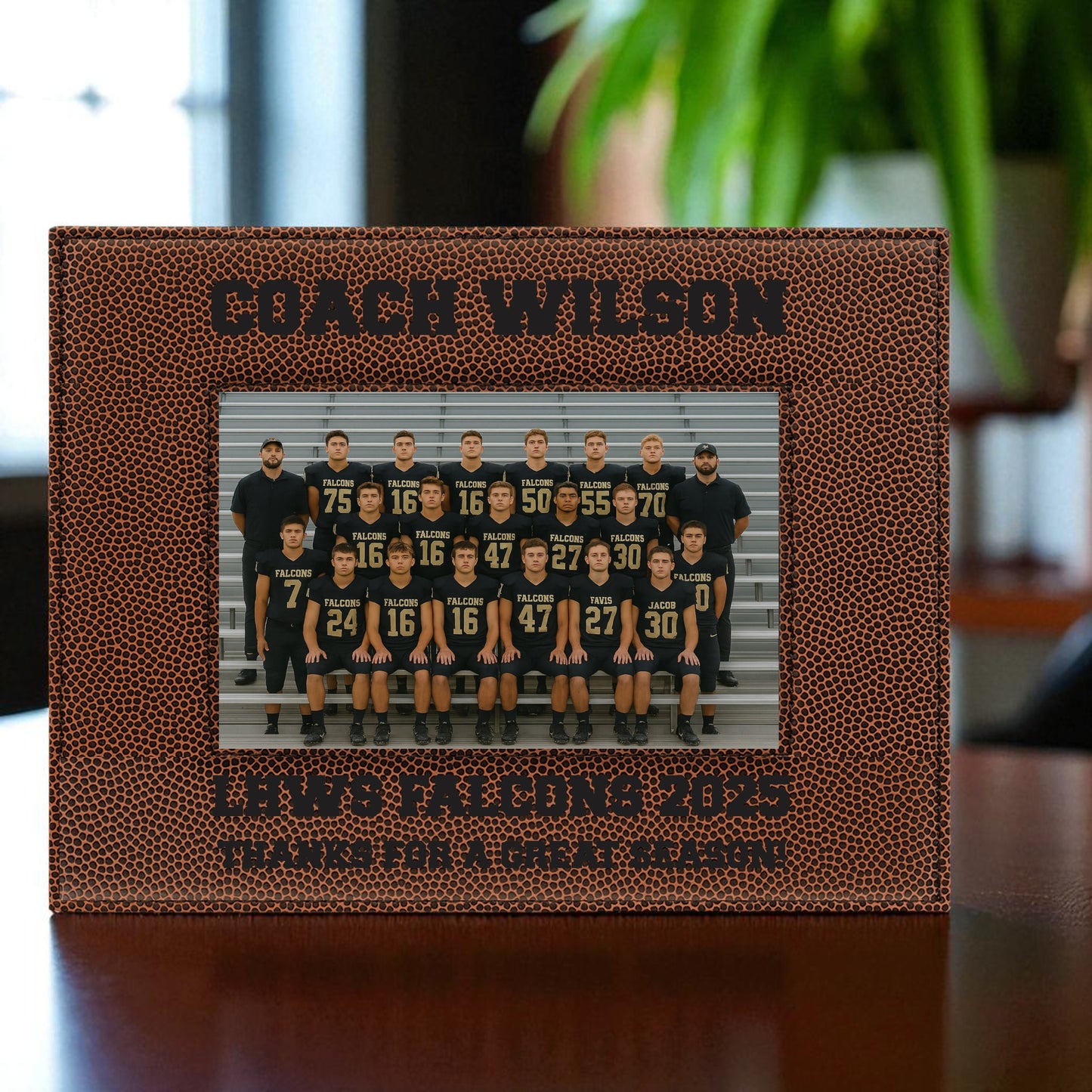Football-themed photo frame with a team picture and engraved text on a wooden surface.